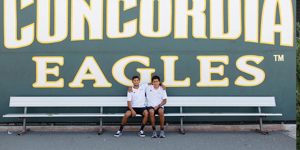 The Aguirre brothers sitting in front of the Concordia Eagles sign
